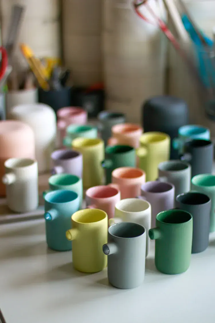 Row of slip-cast pieces drying on studio shelf